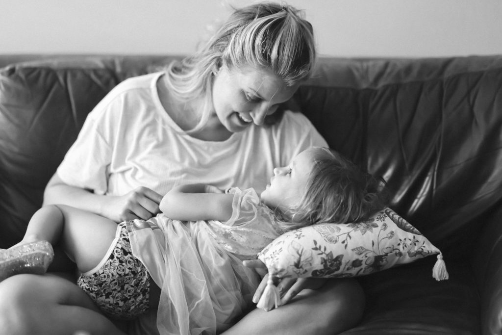 family moments between a mother and daughter playing on the couch in black and white