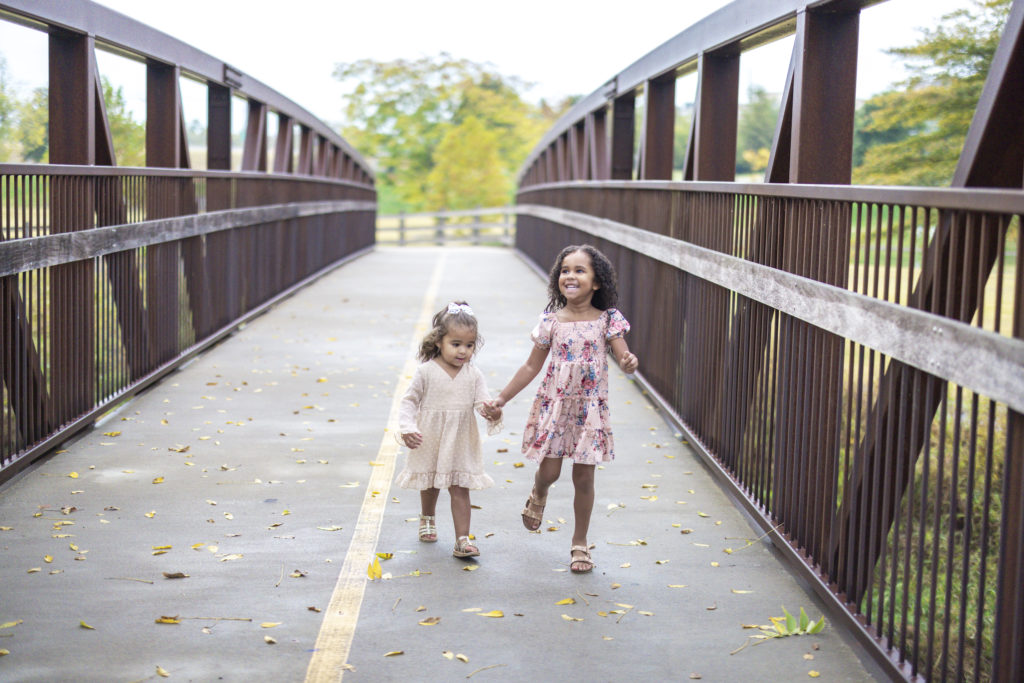 Mommy and Me Photo Session with two little sisters walking on a bridge.