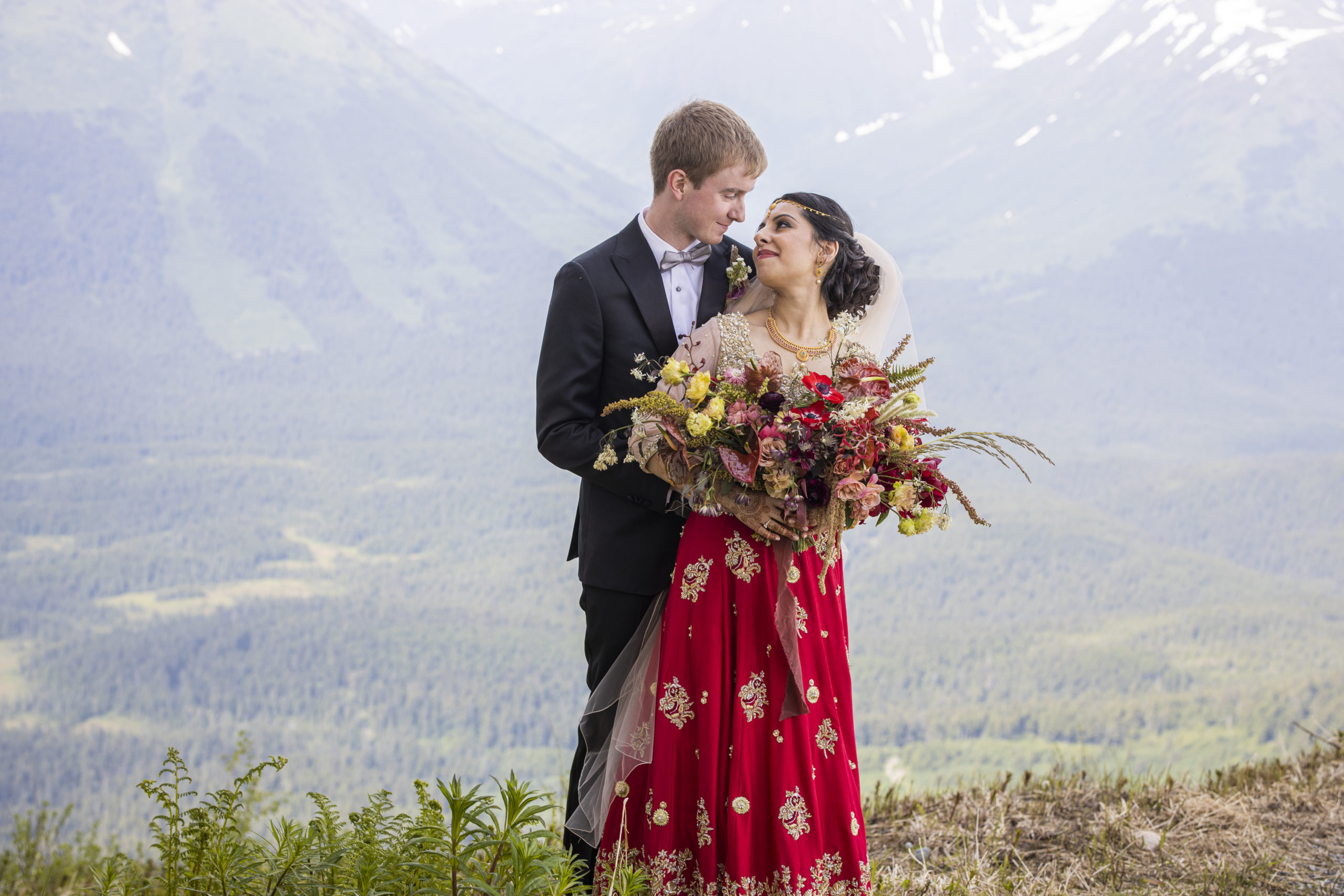 Wedding at Alyeska Resort in Girdwood Alaska with a Pakistani bride and Alaskan groom holding each other on mountaintop