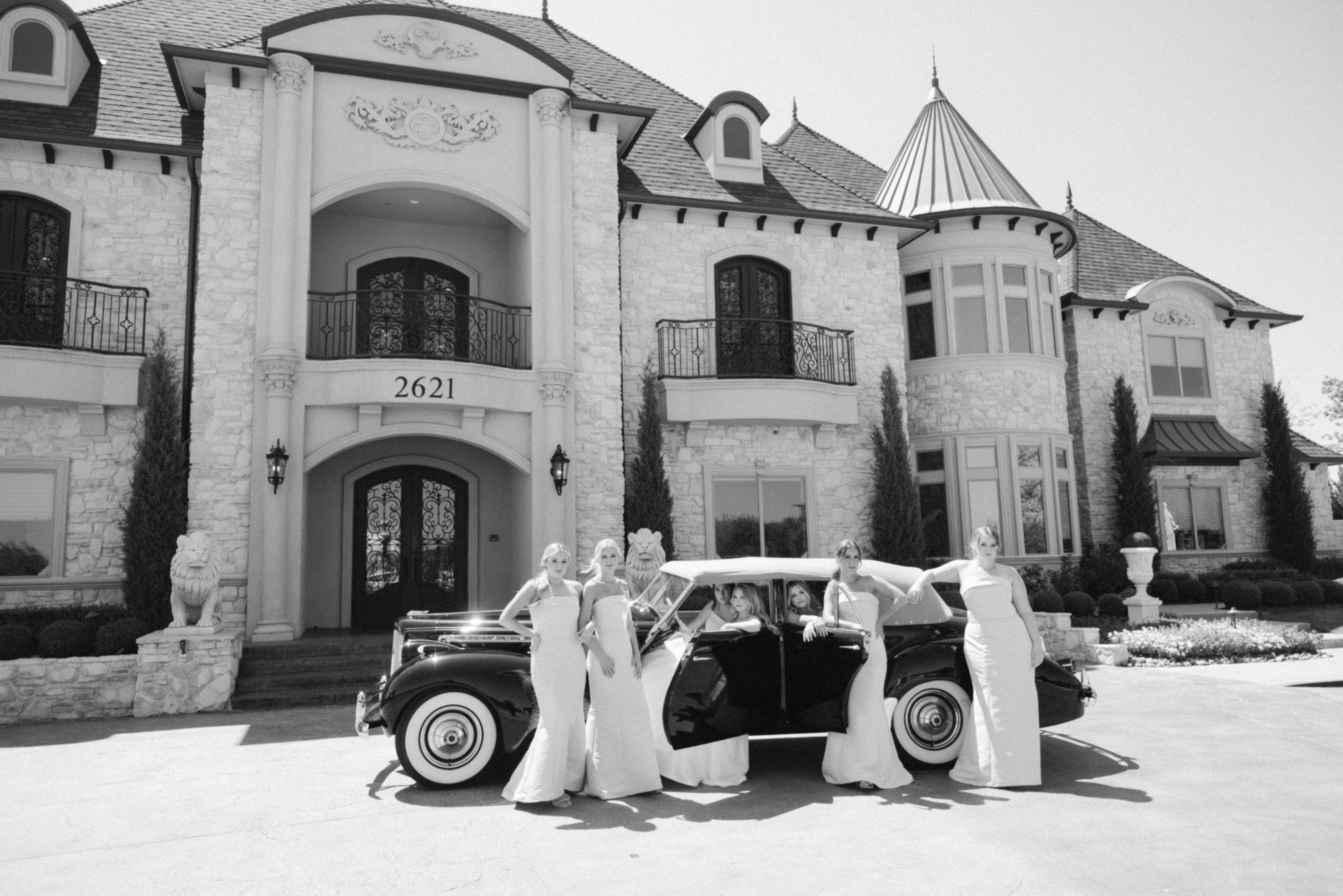 Bridesmaids and bride in a vogue like photo shoot on her wedding day at Knotting Hill Place done in black and white around a vintage car.