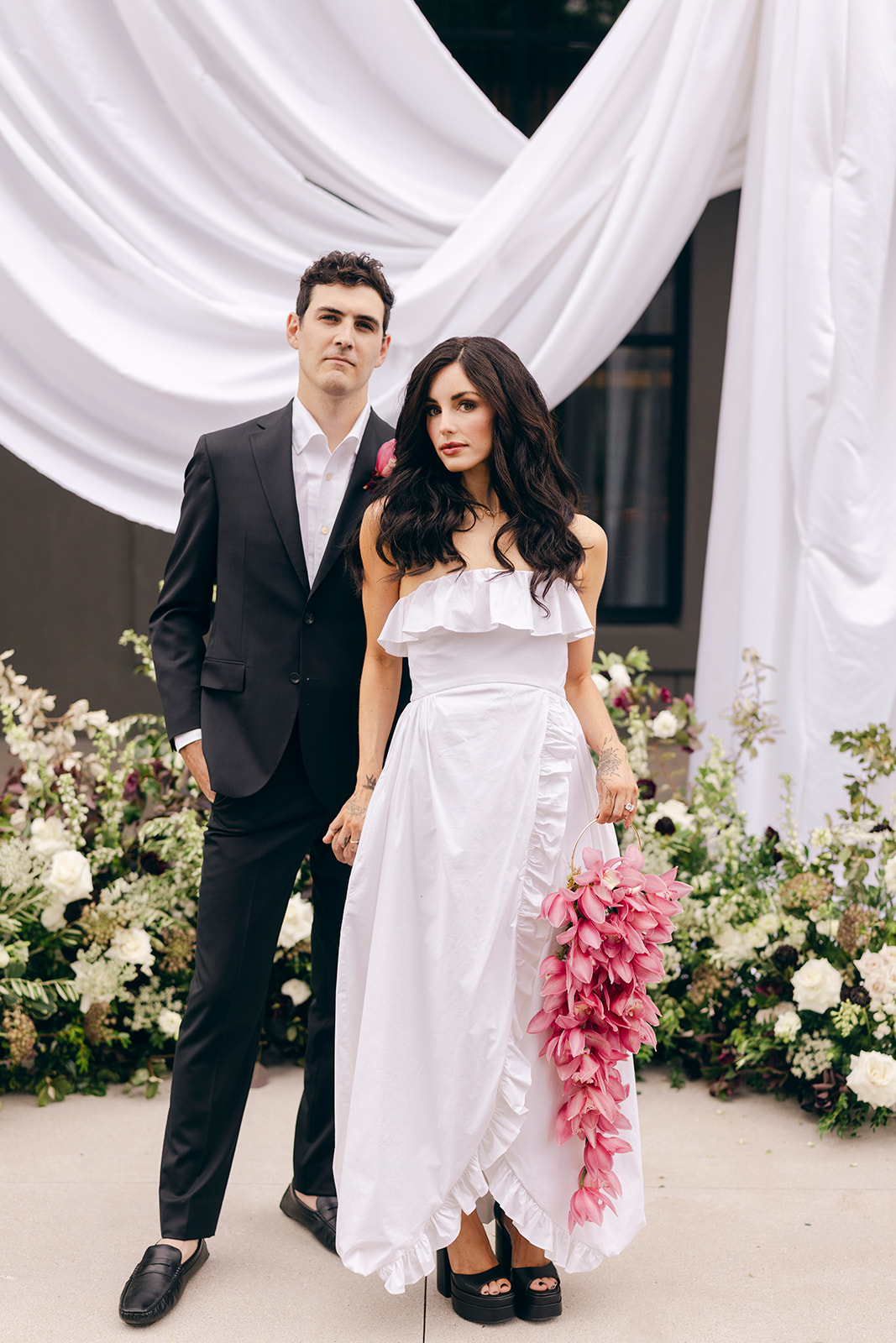 Bride and groom posing beneath white draping and floral installations at Hotel Vin Rogers.
